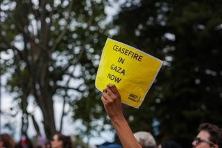 a person holds a sign calling for a ceasefire