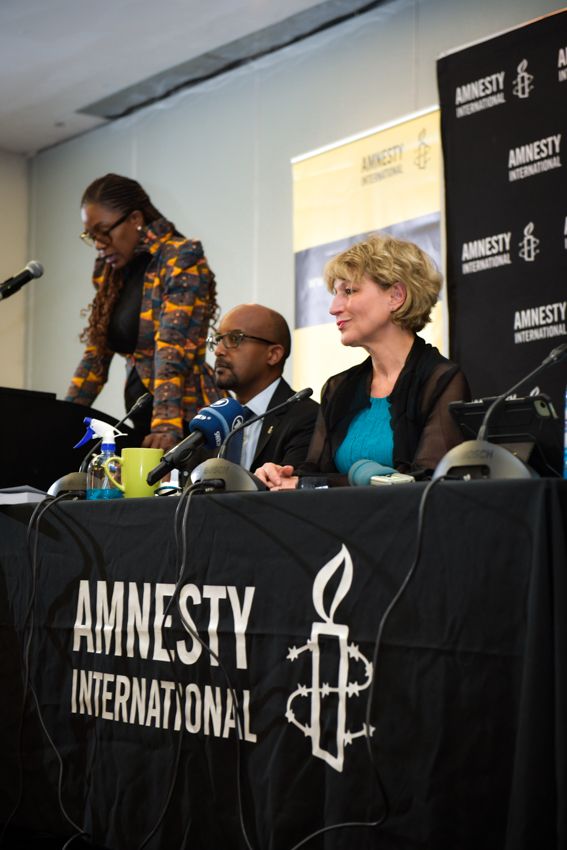 Amnesty leaders sit in a conference