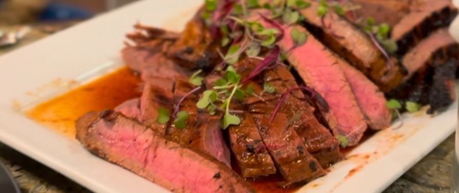 Sliced steak on a platter with microgreens