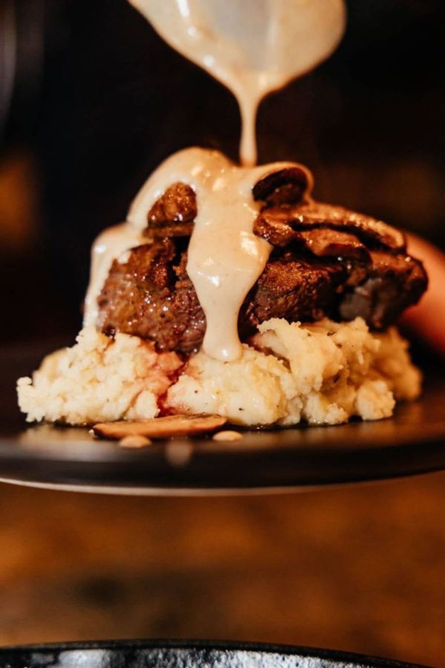Steak with gravy poured over whipped potatoes