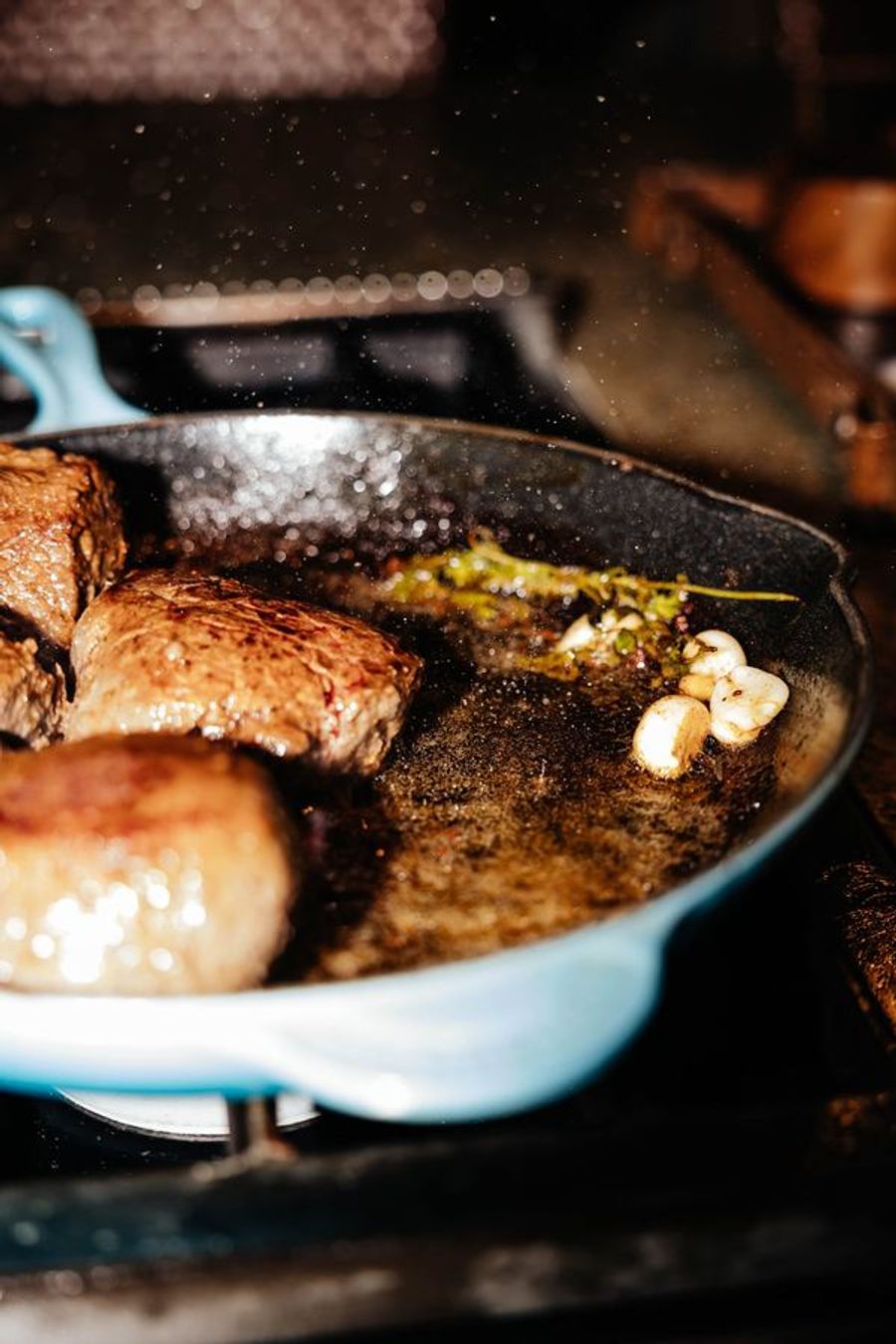 Steaks searing in a skillet with rosemary