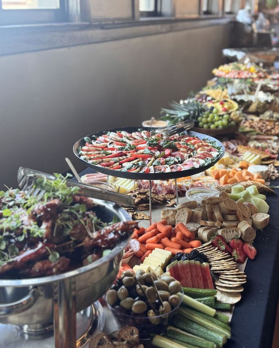 Long table of appetizers, charcuterie, and fresh vegetables