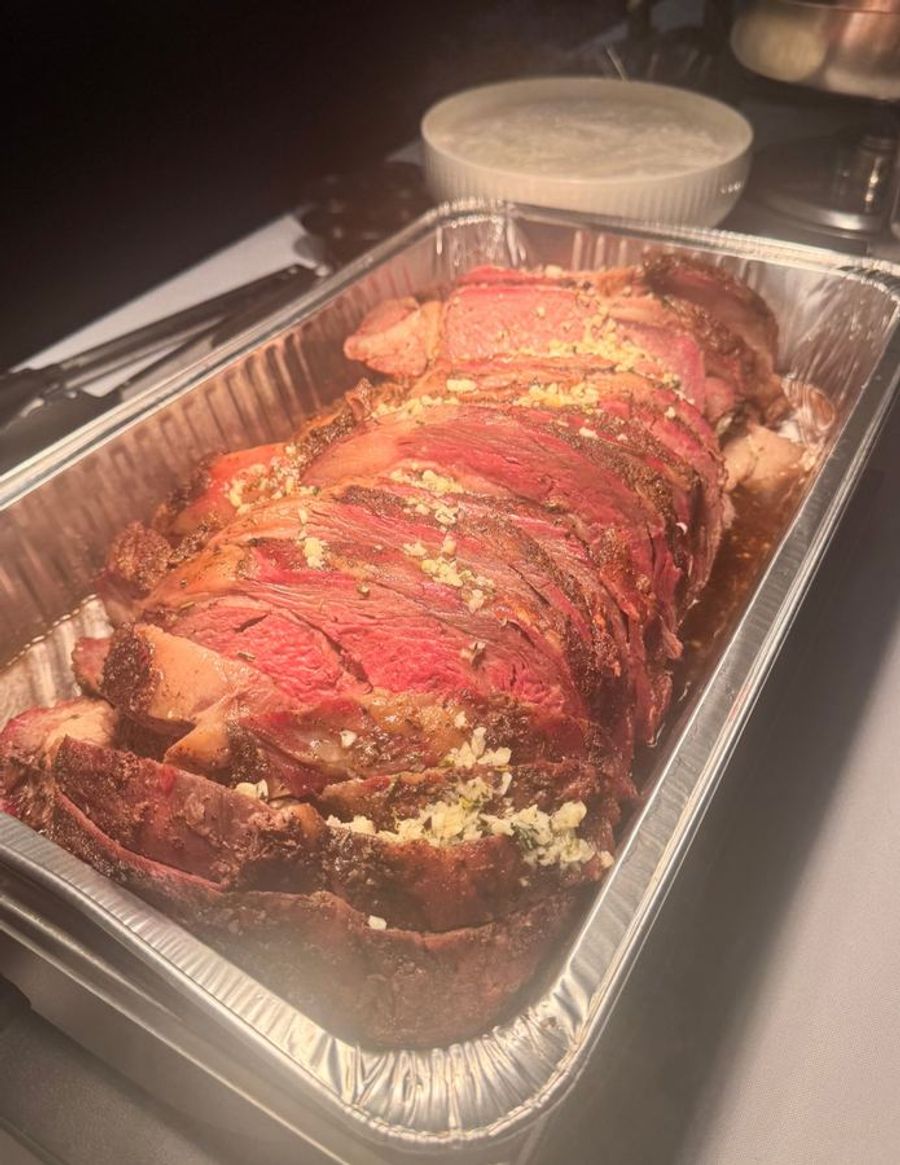 Sliced prime rib with garlic herb butter in a serving pan