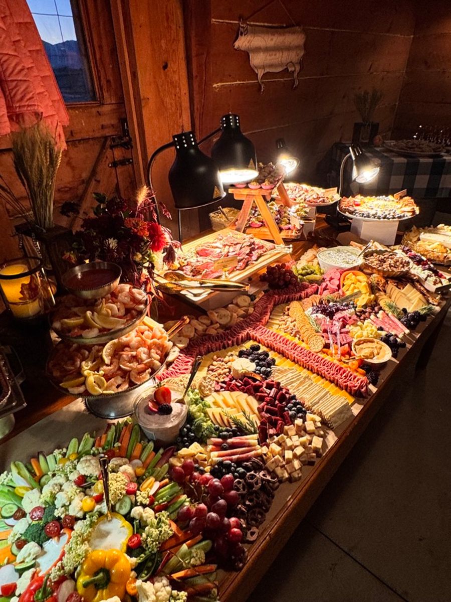 Grazing table laid out under warm lights in a barn