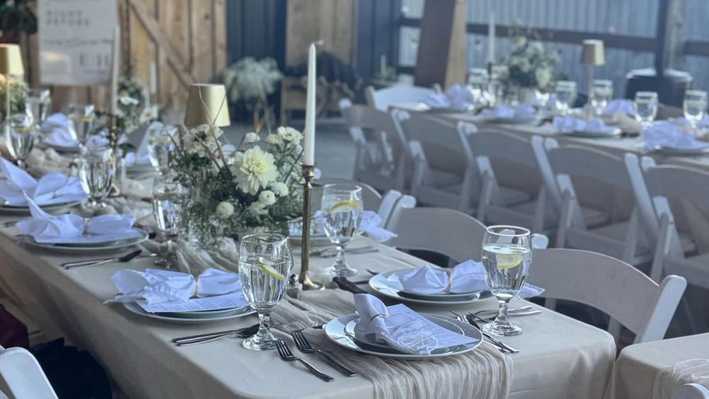 Long reception table set in a barn with candles and florals
