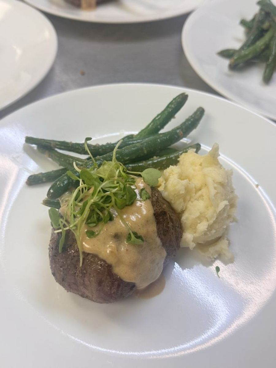 Plated steak with whipped potatoes and greens