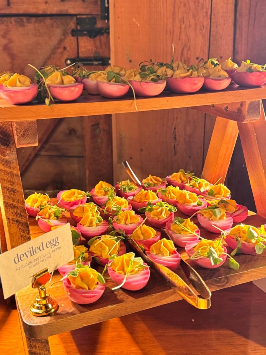 Beet pickled deviled eggs on a tiered wooden stand