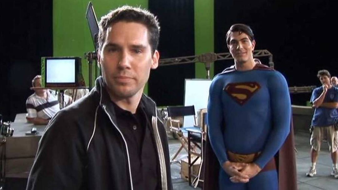 A man in a Superman suit is standing alongside a disgraced director.