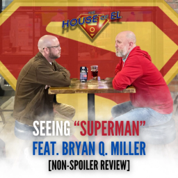 Two men sit at a table in front of a Superman logo.