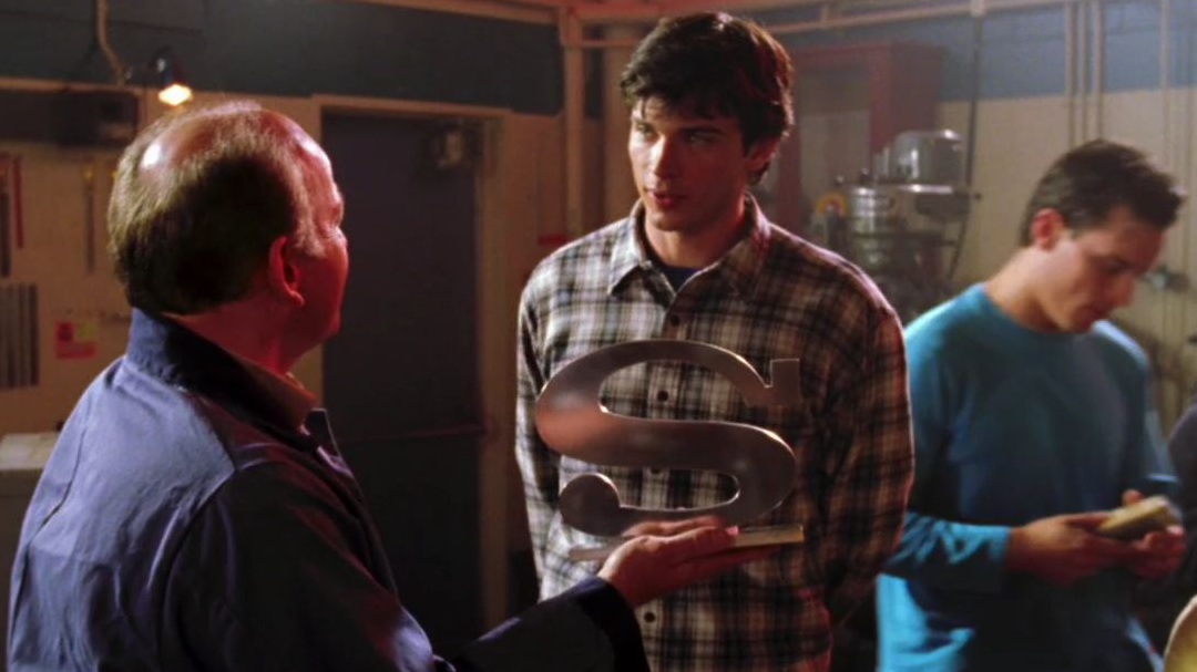 a metal s in smallville shop class being held in front of clark kent.