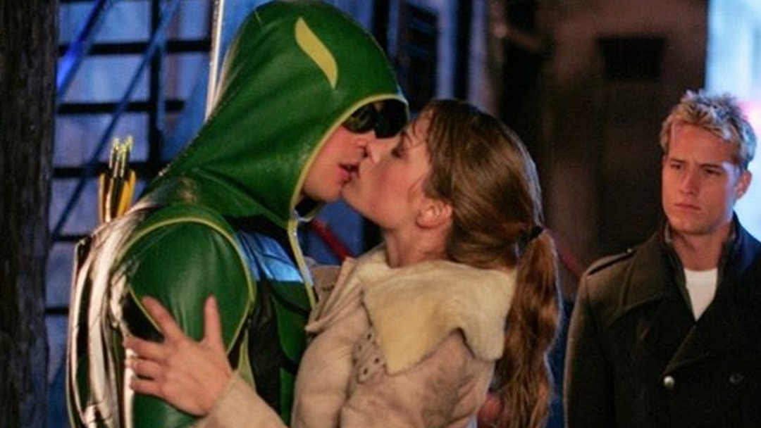 Oliver Queen watches as Lois and Clark kiss, the latter dressed like Green Arrow.