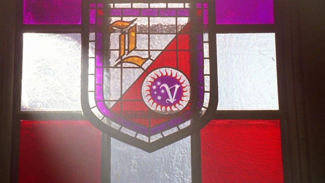 A stained glass window with an L and a V inside a shield.