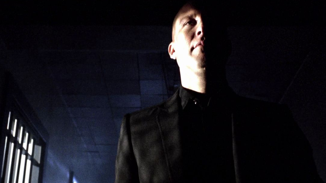 A bald man walks down a hallway.