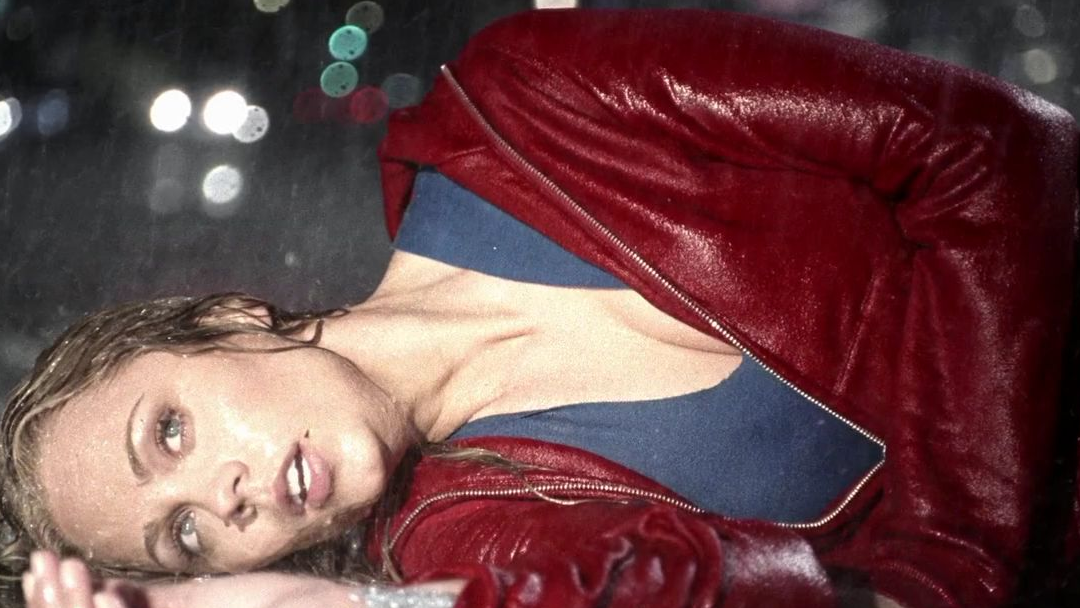 A young woman laying on the ground in the rain.