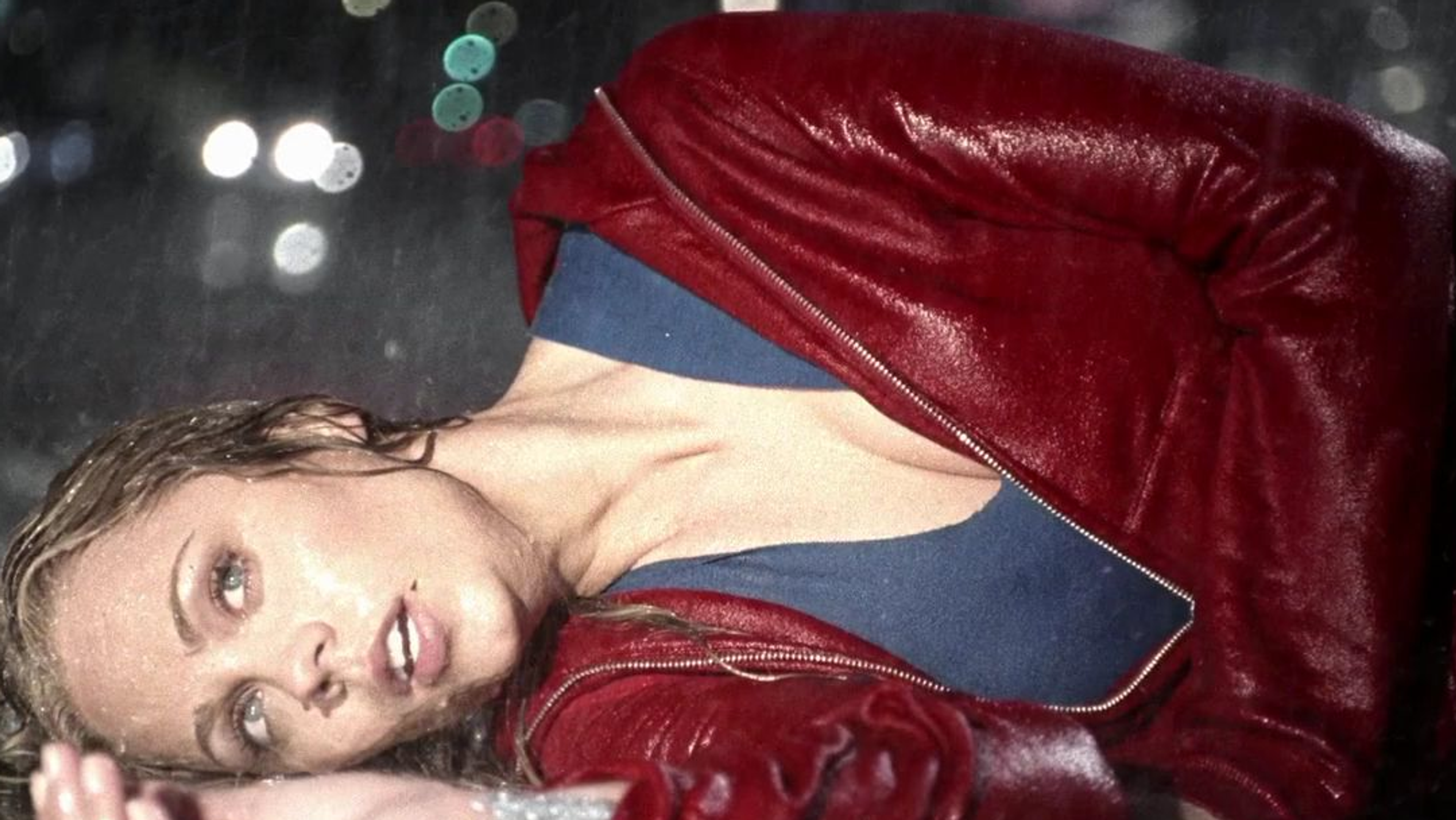 A young woman laying on the ground in the rain.