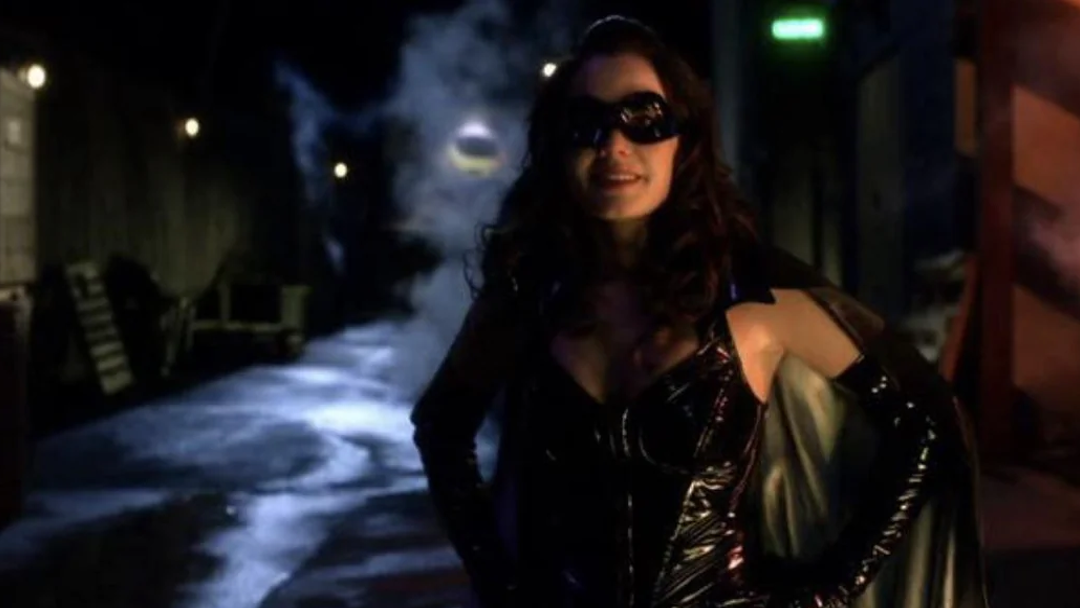 A woman in a leather outfit with a cape and mask.