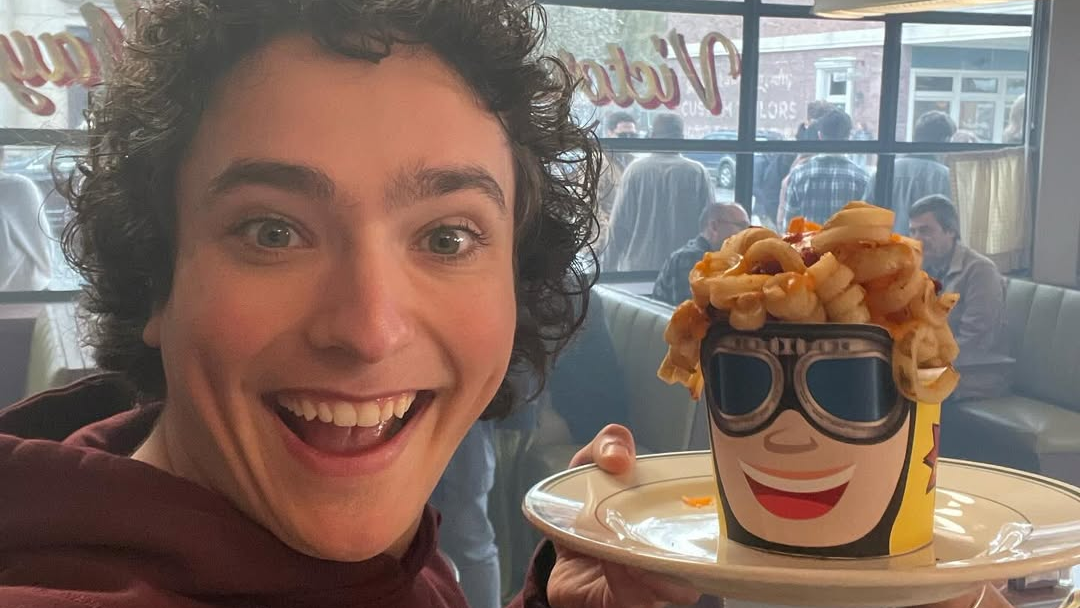 Alex Garfin holding a prop bucket of curly fries shaped like his head.
