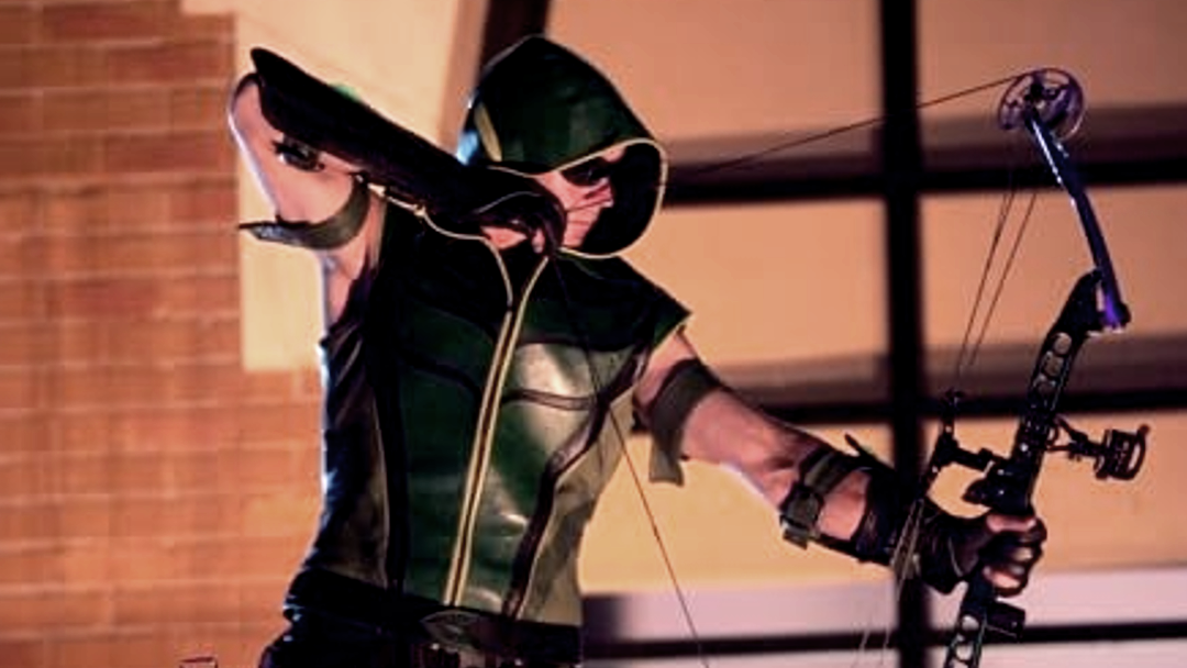 An archer in green leather aims his bow.