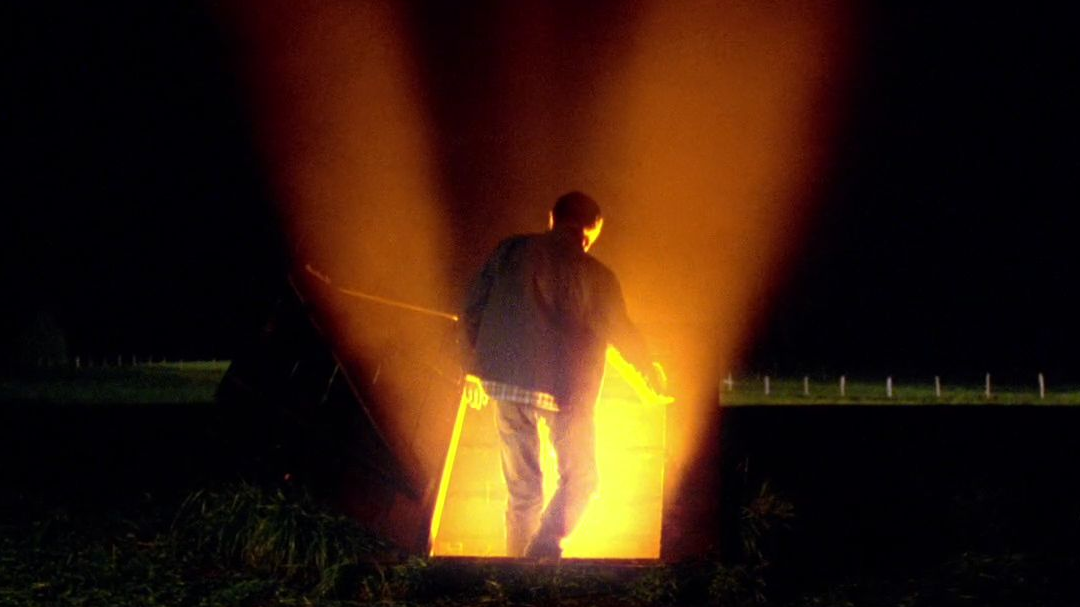 clark kent opening the storm cellar which is illuminated by the ship