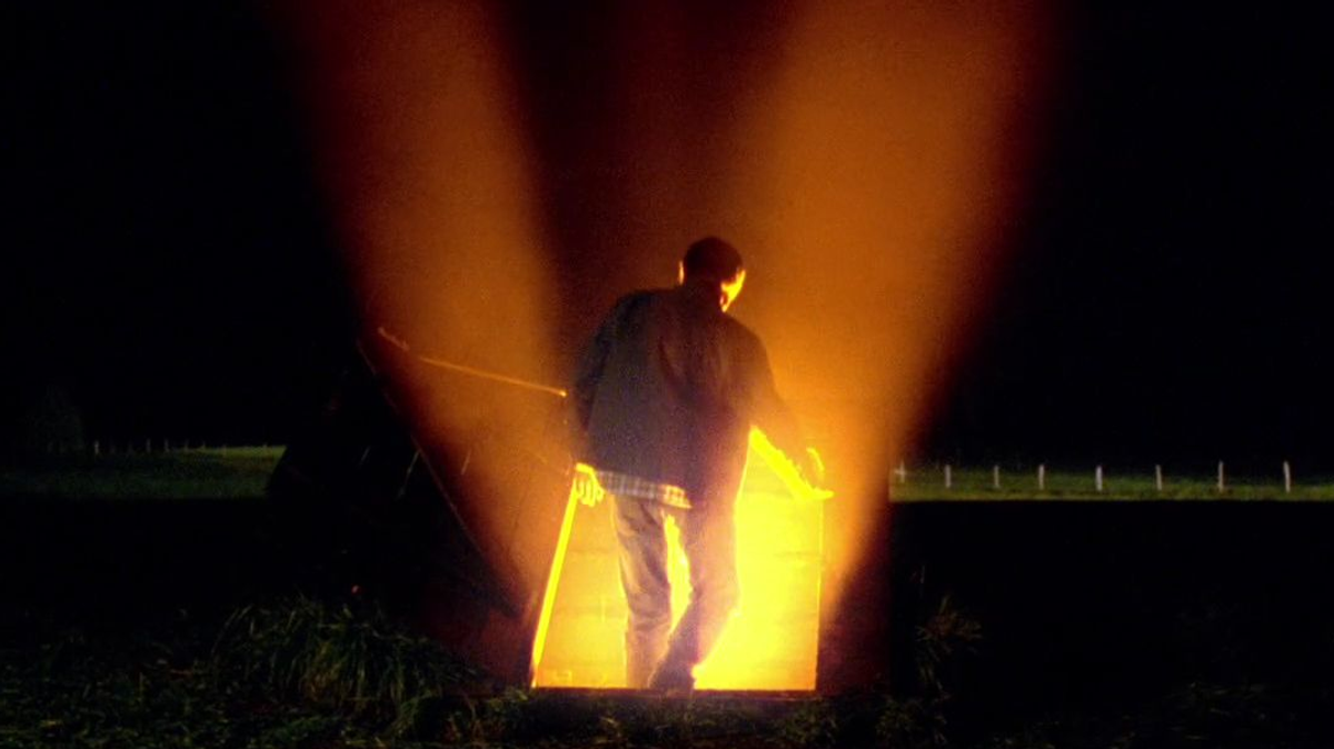 clark kent opening the storm cellar which is illuminated by the ship