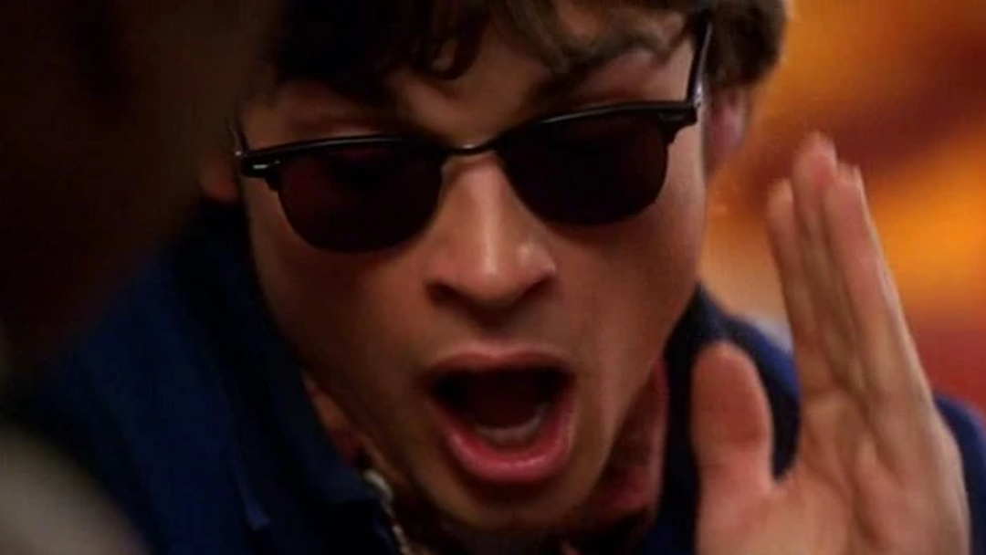 A young man in sunglasses is shocked at what he hears.