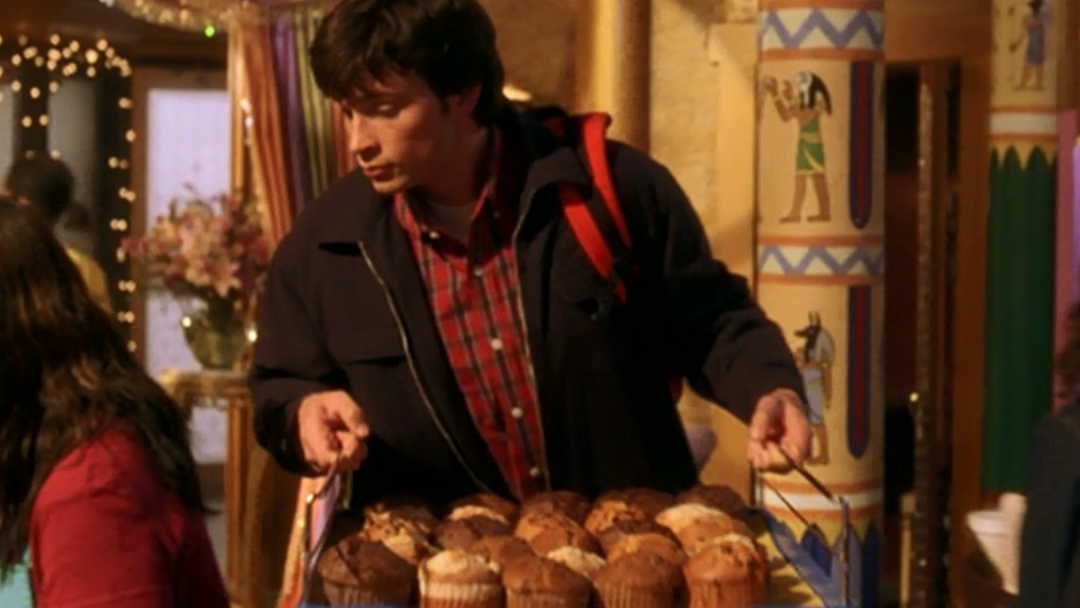 A young man carrying a tray of muffins.