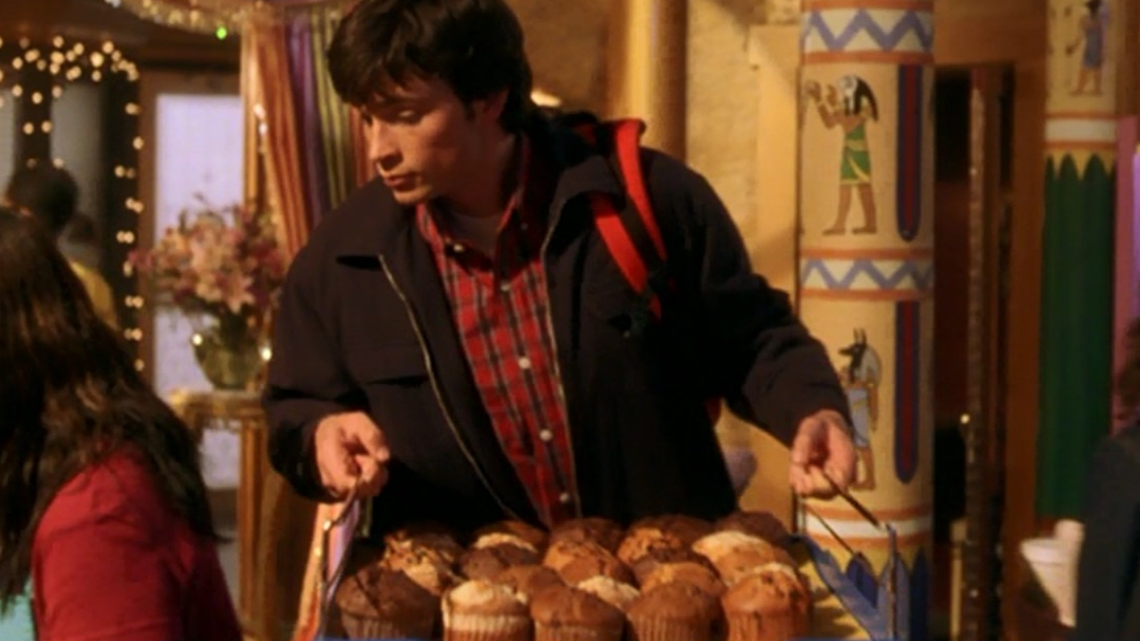 A young man carrying a tray of muffins.