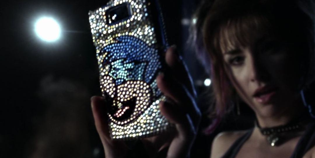 Jayna of the Wonder Twins holding a phone with Gleek the monkey on it.