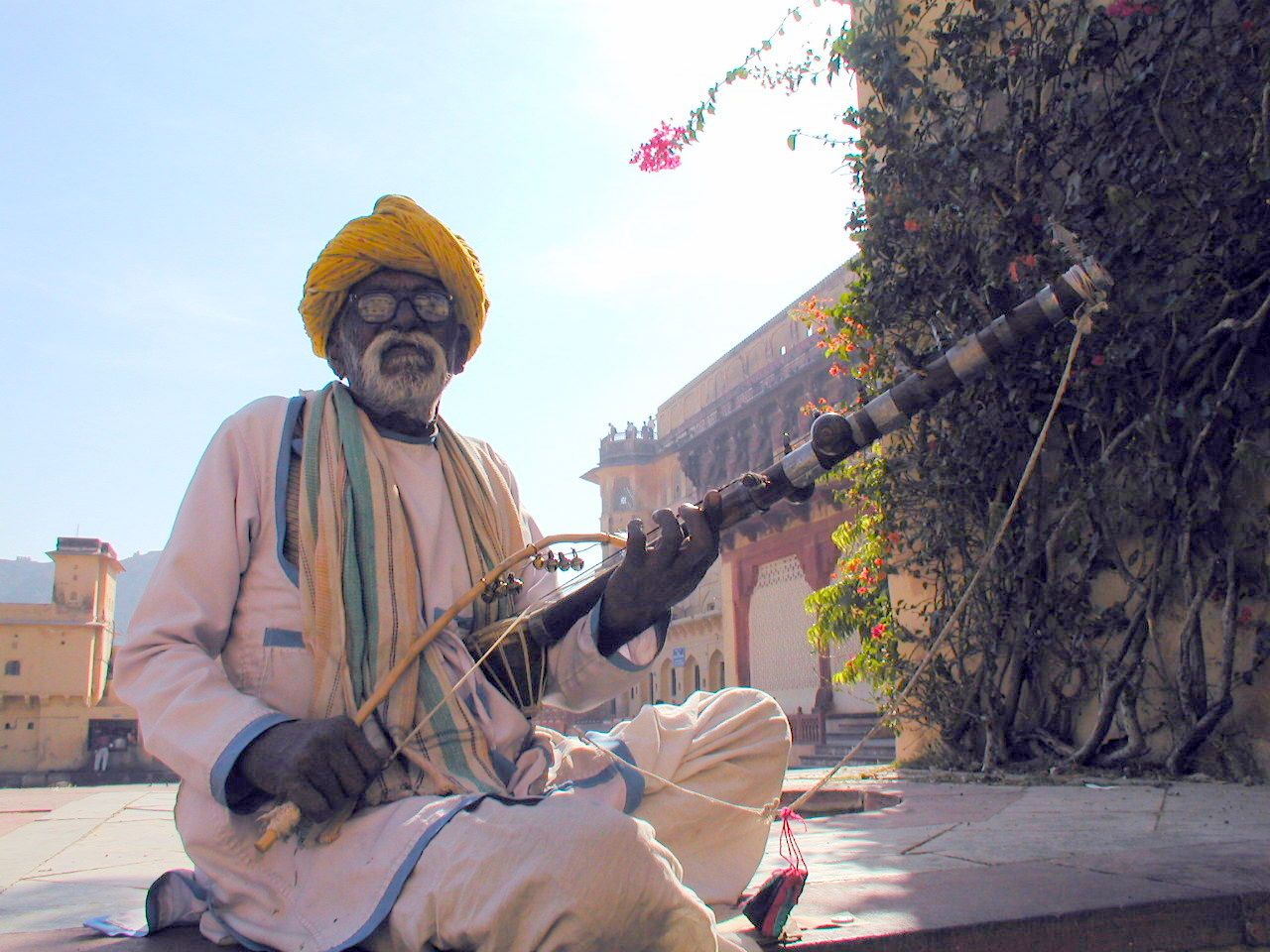 Un hombre con turbante amarillo sentado al aire libre.