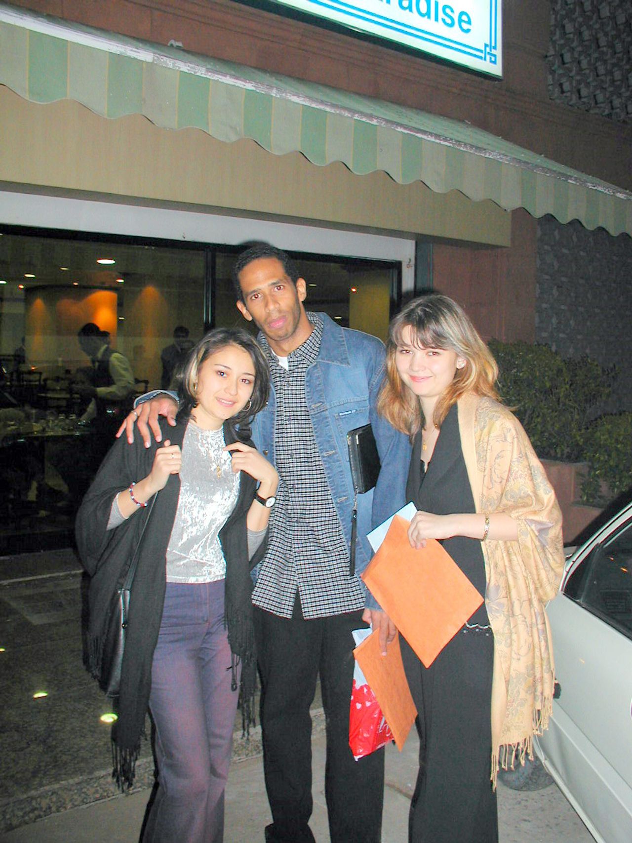 Tres compañeros posan de noche frente a un edificio.
