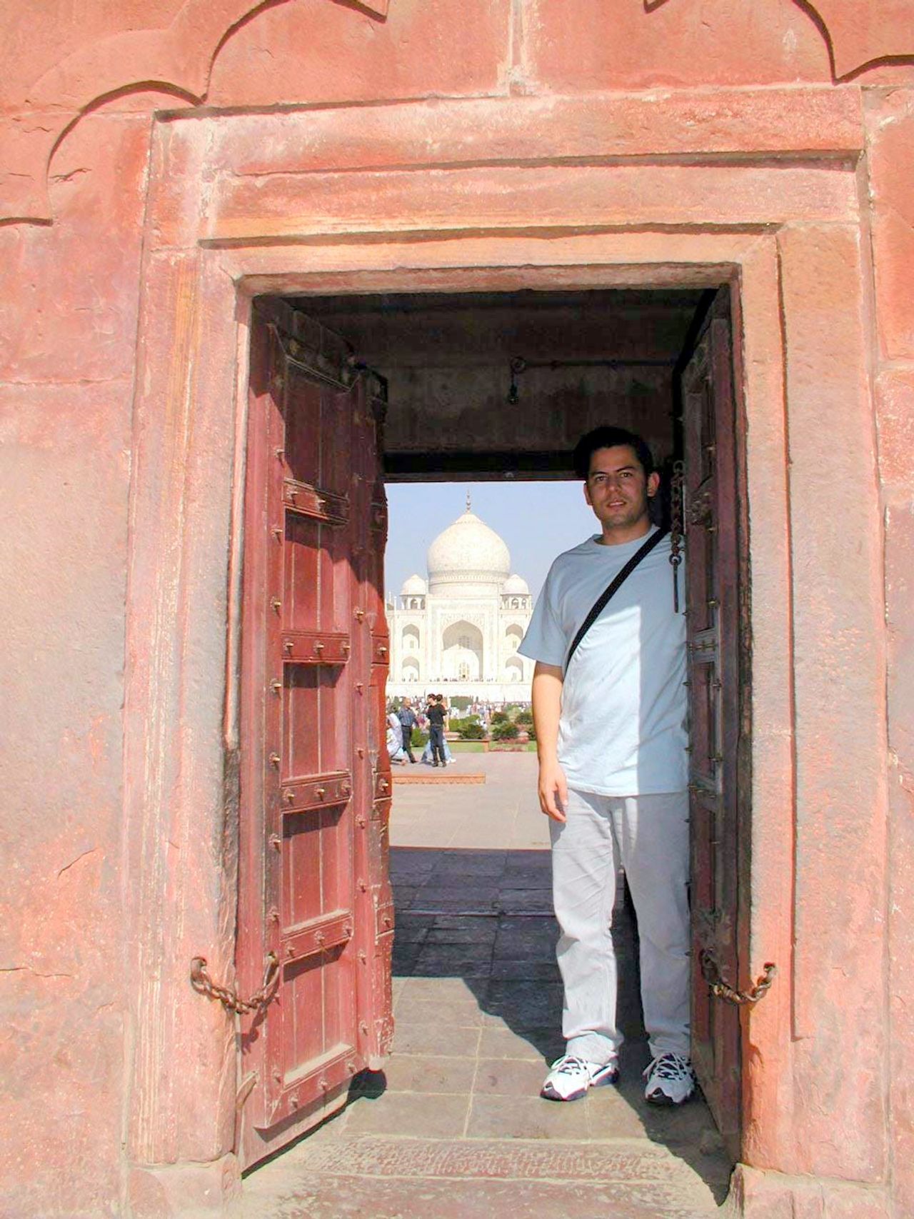 Un visitante bajo una pequeña puerta de piedra roja.