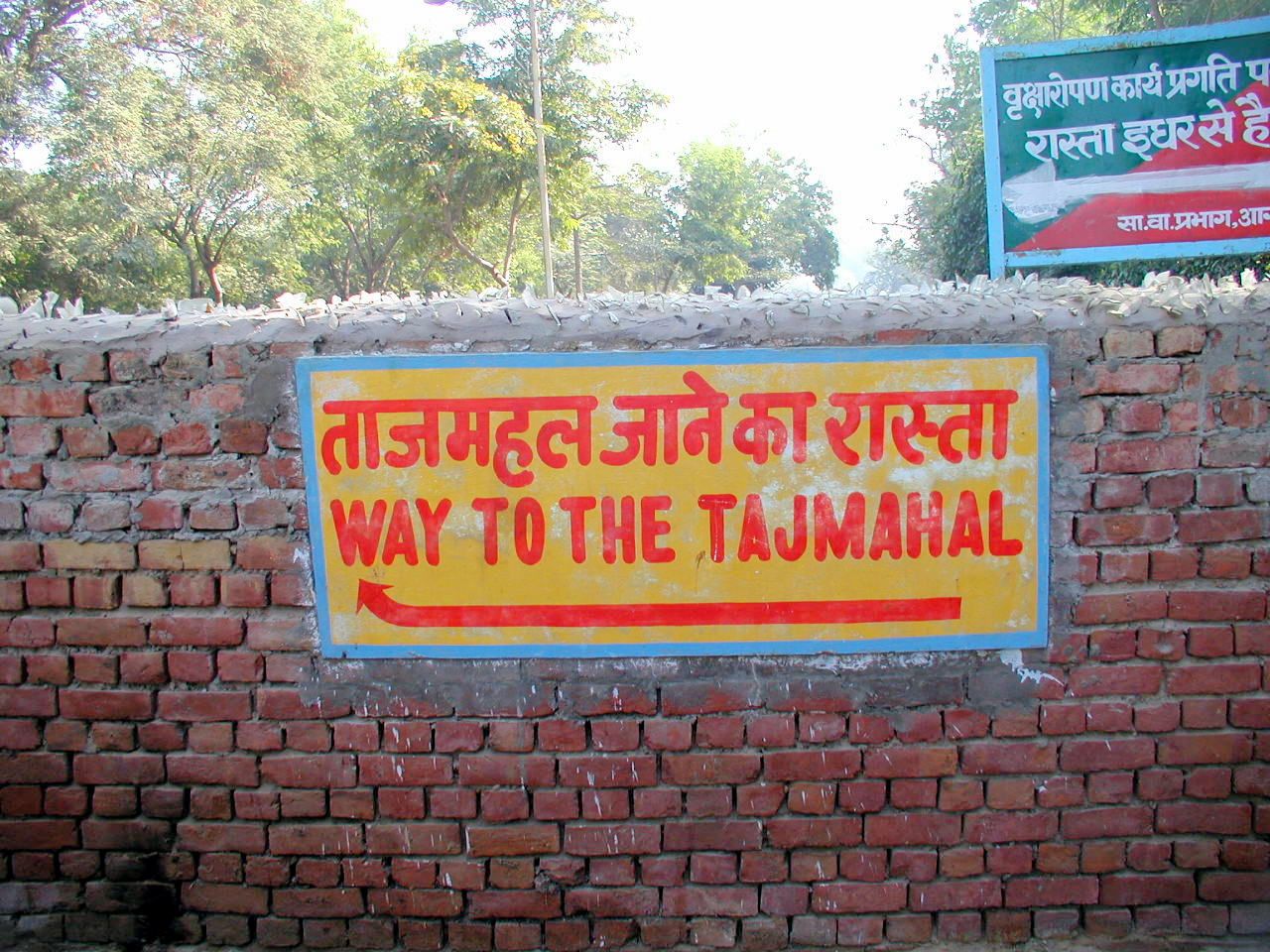 Señal con una flecha que indica el camino al Taj Mahal.