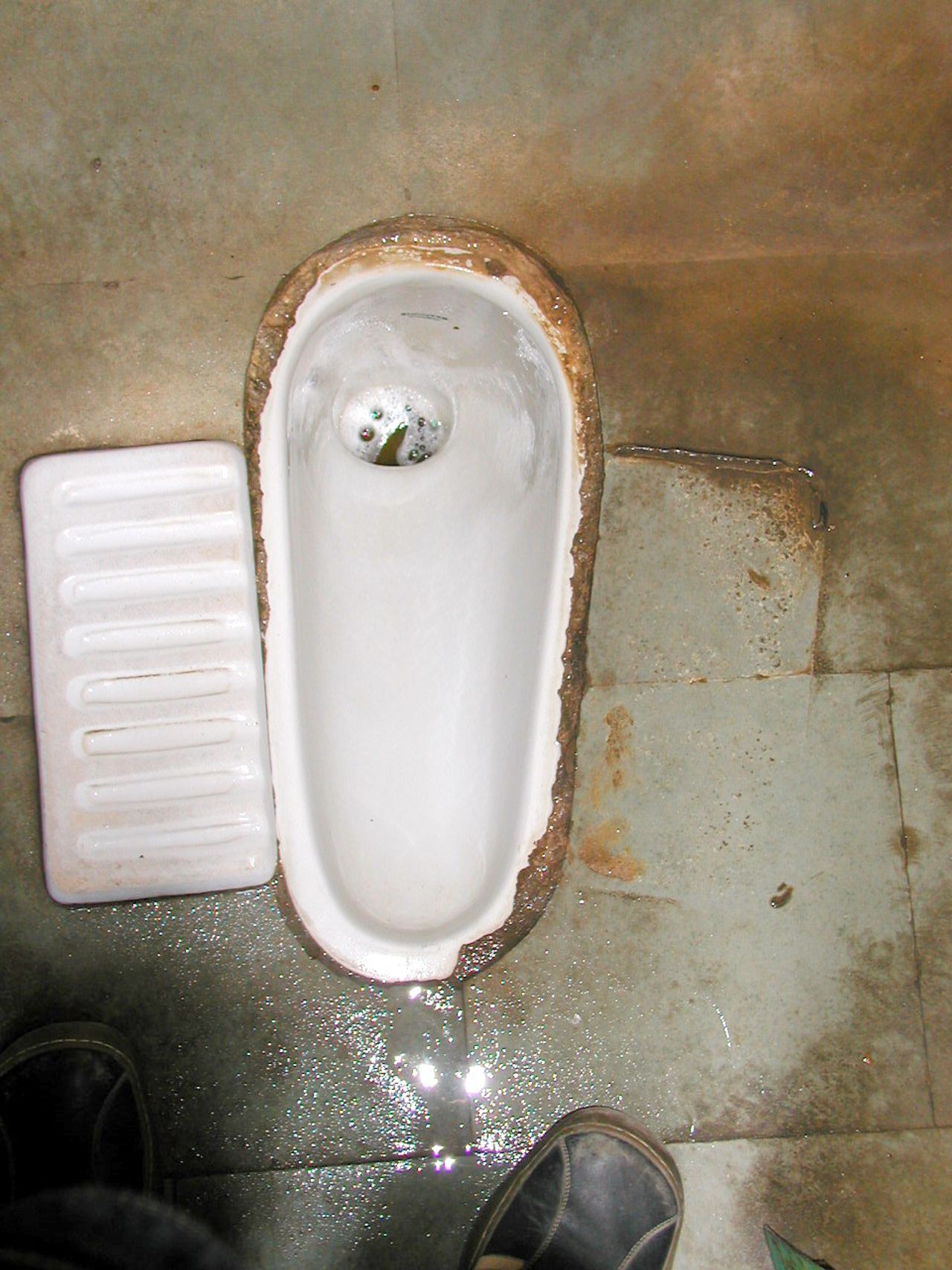 Un sanitario a ras del suelo junto a un grifo.