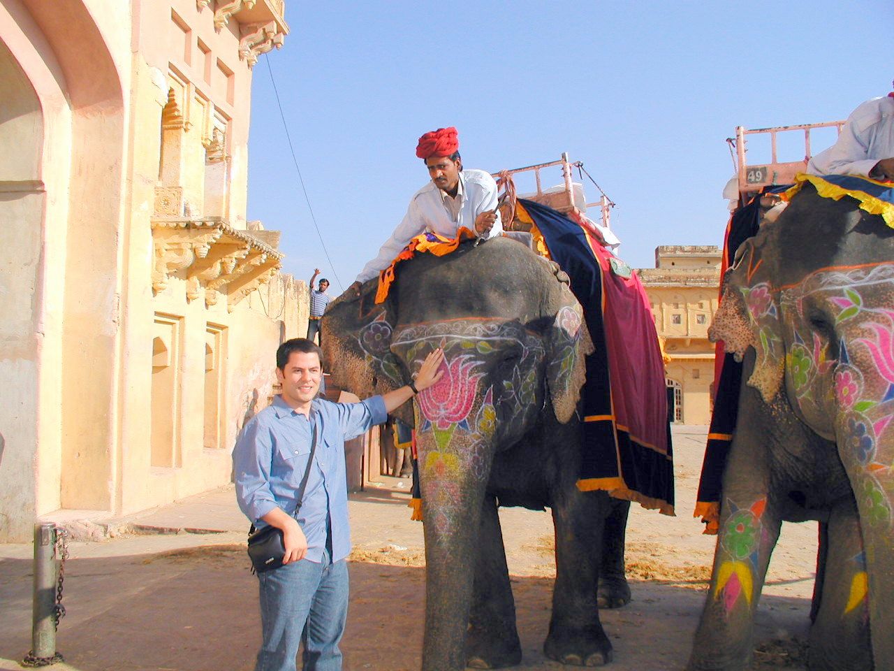 Un viajero junto a un elefante equipado para transportar visitantes.