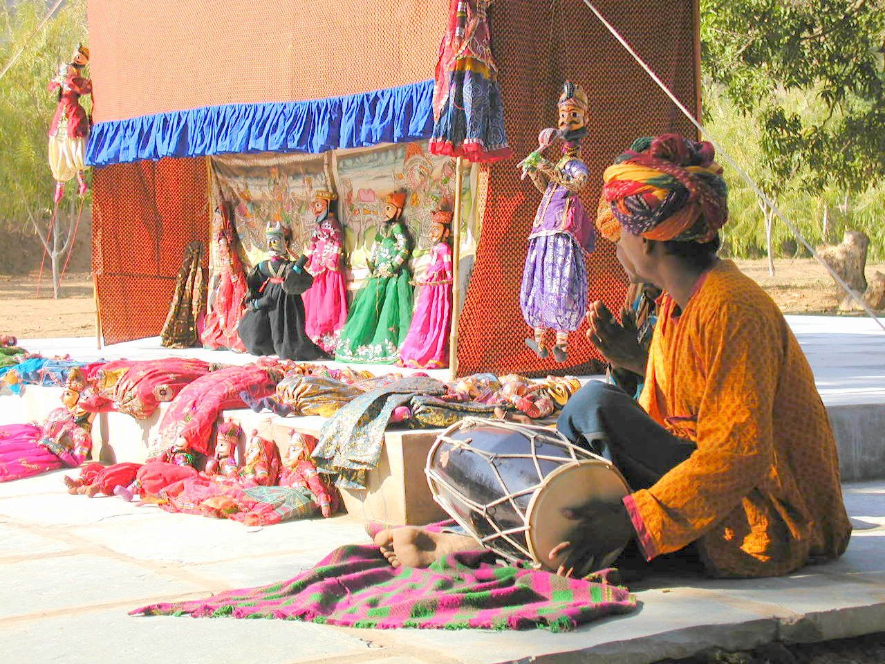 Un comerciante sentado junto a telas y artesanías de colores.