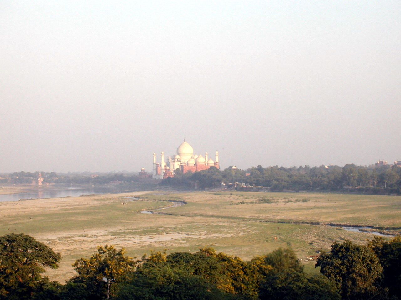 El Taj Mahal a lo lejos, al otro lado de una extensa llanura.