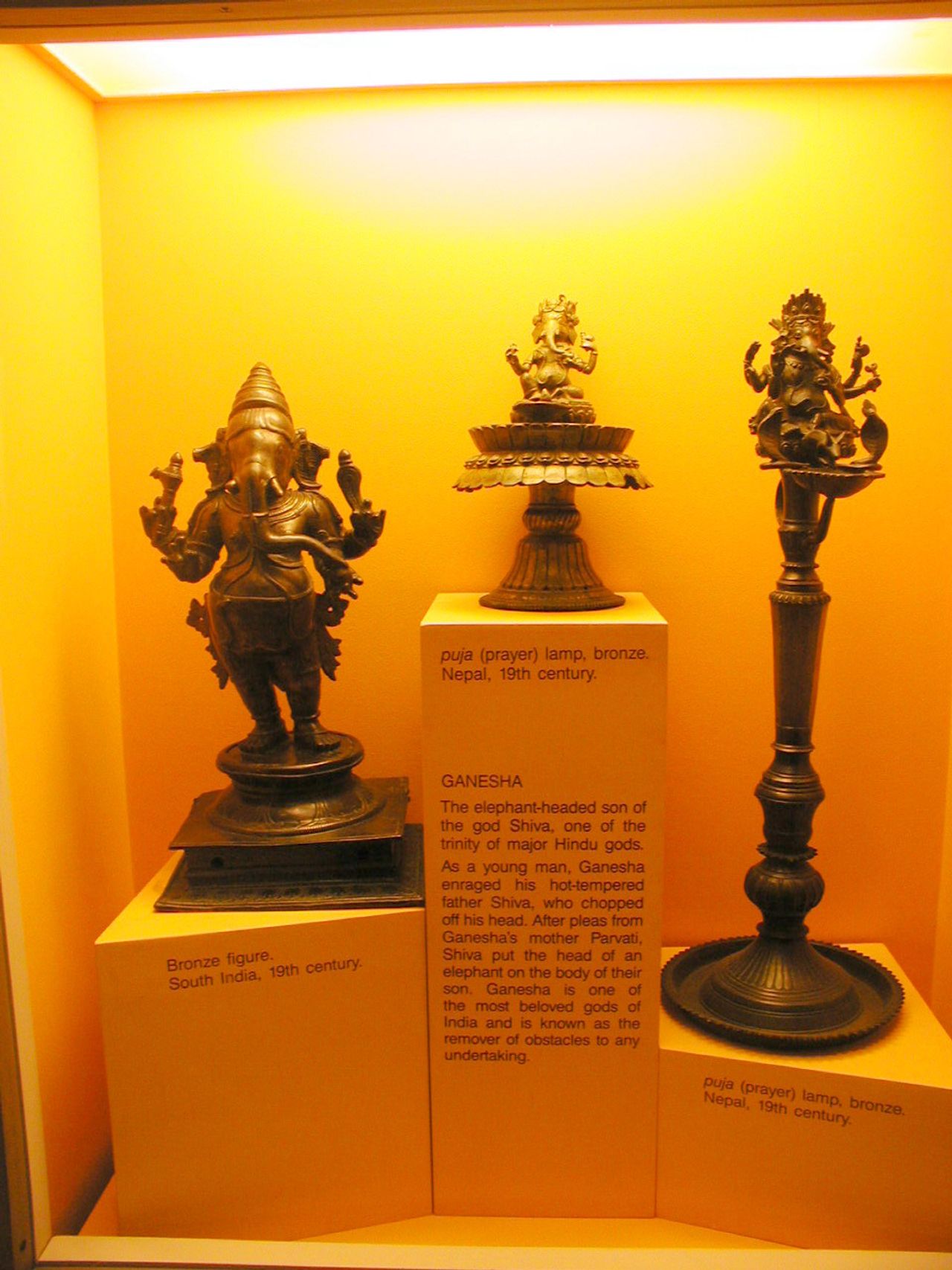 Objetos decorativos y figuras expuestos en una vitrina iluminada.