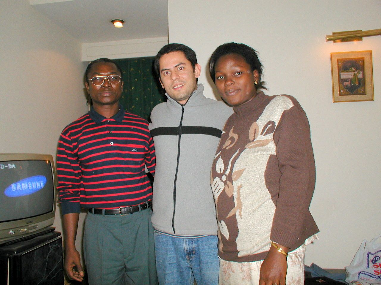 Tres compañeros posan juntos en una habitación.