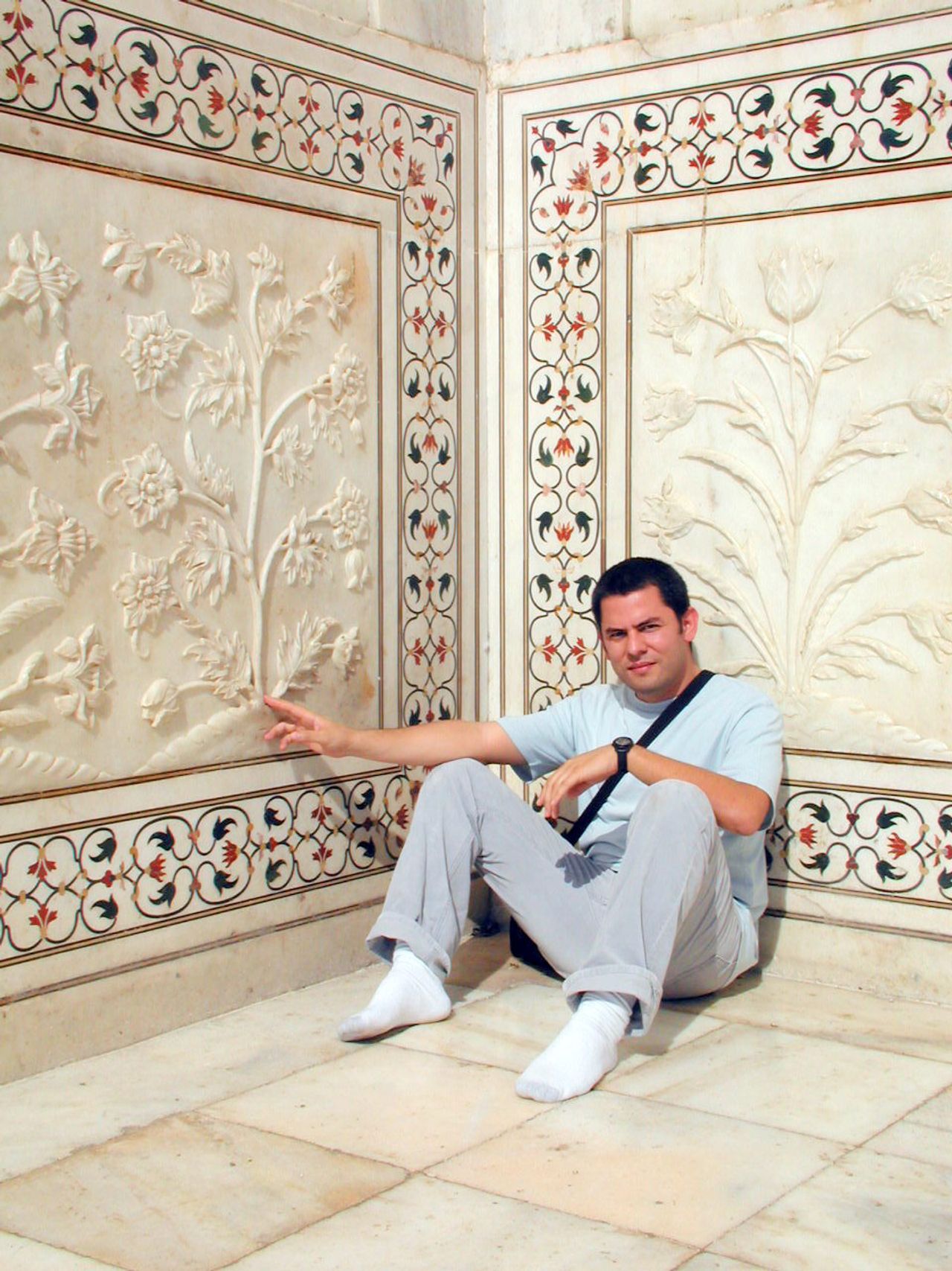 Un viajero sentado junto a los relieves de mármol del Taj Mahal.