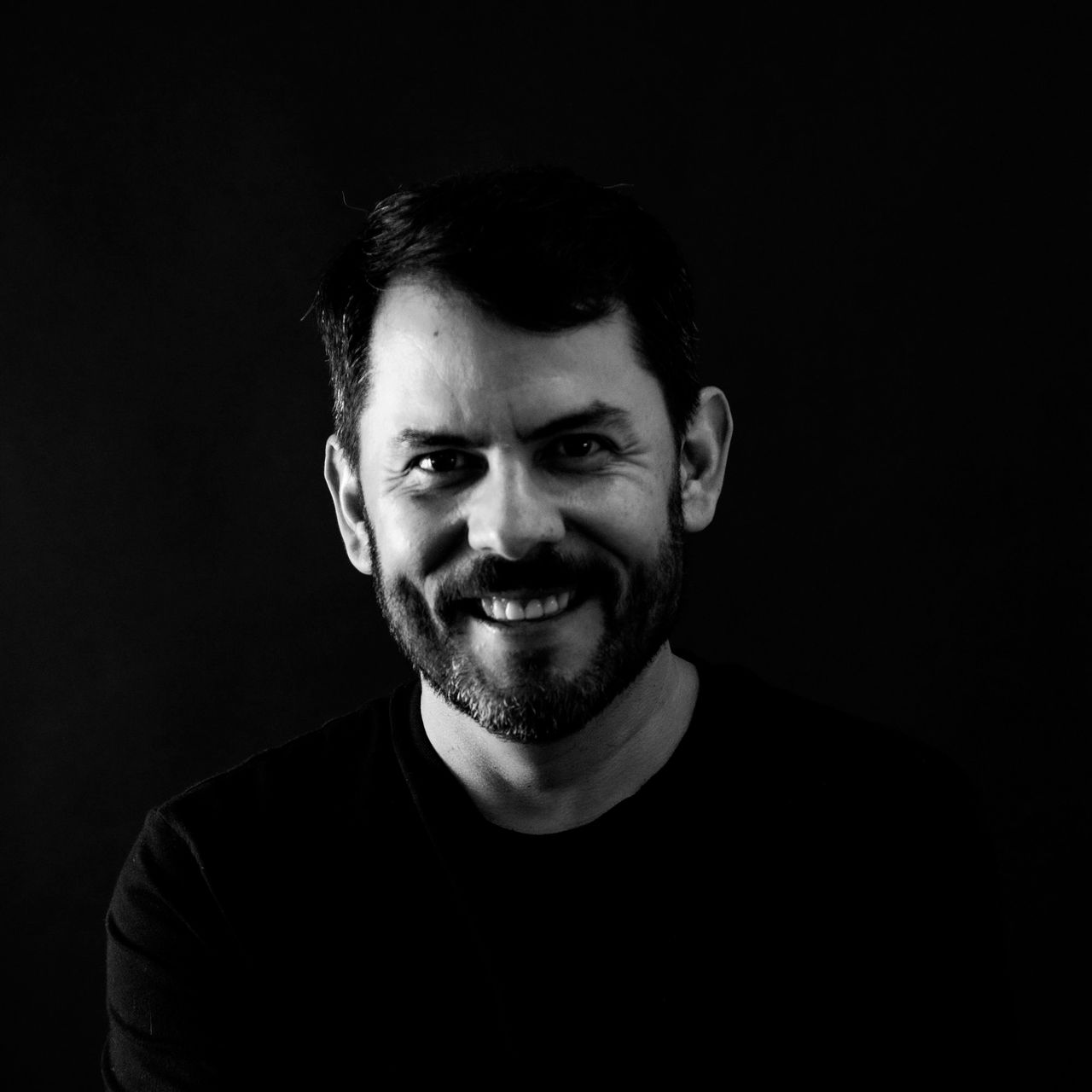 Black-and-white portrait of Víctor Yoalli smiling, photographed by José Cid.