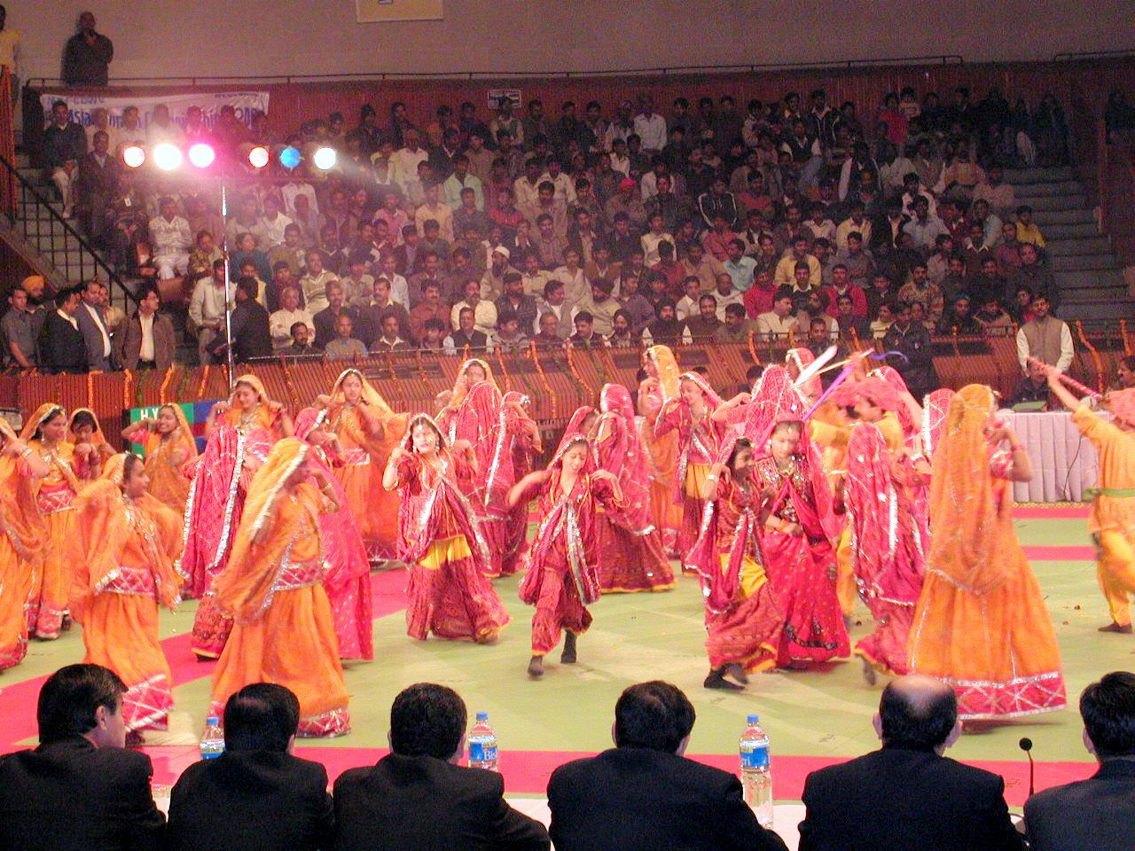 Presentación de baile con un grupo de artistas vestidos de rojo y rosa.