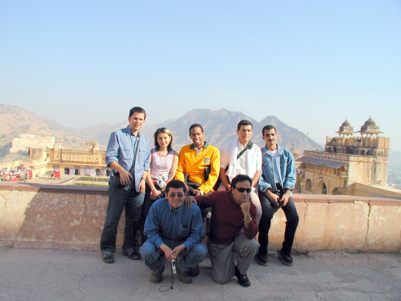 Grupo de compañeros posando sobre un muro con las montañas al fondo.