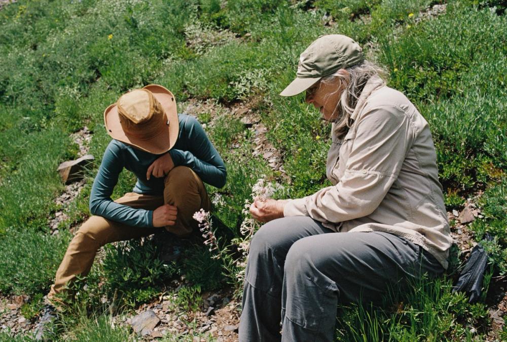 scientists sit atop the rocky mountains holding flowers