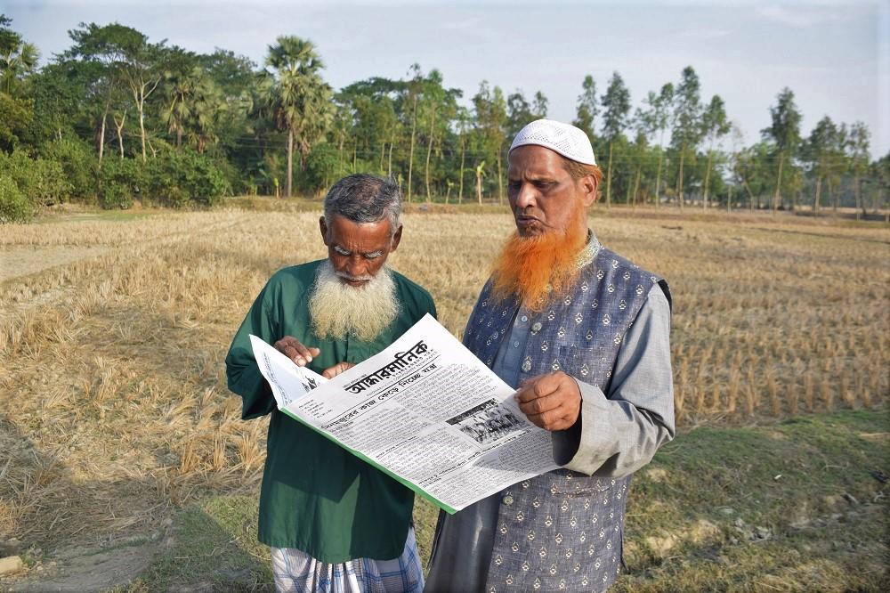 two farmers in a field reading Andharmanic