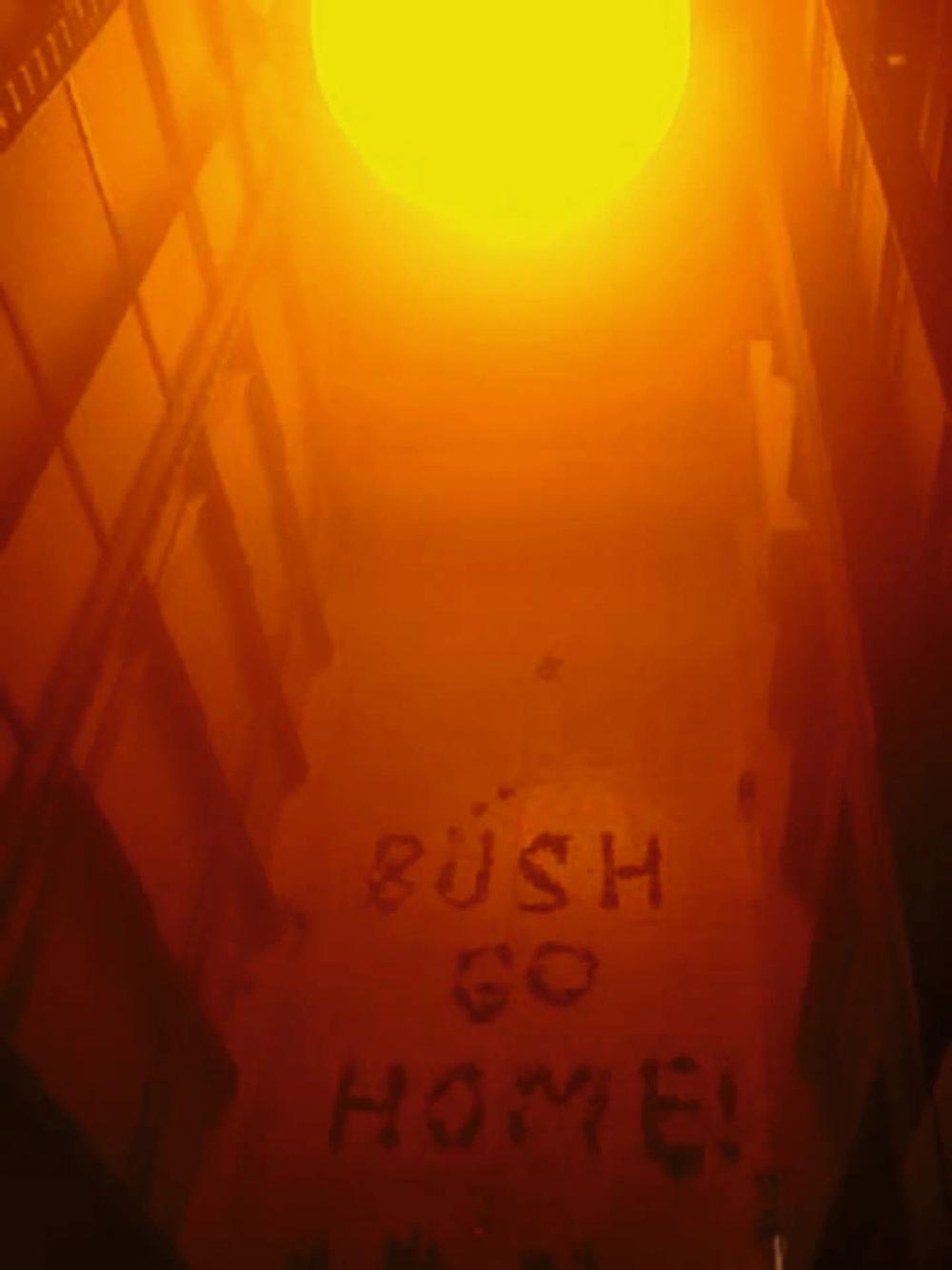 Bush go home, written on the floor in bodies with the giant sun of the weather project overhead