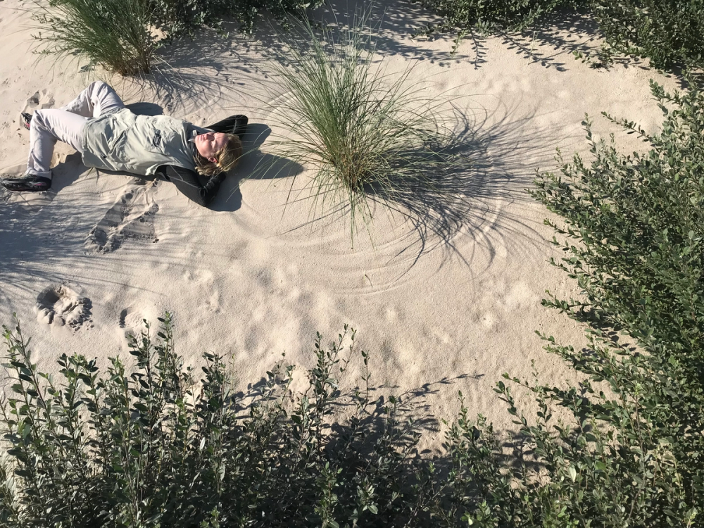 An image of Ingri Hoyland, lying on sand, on what could be a beach.