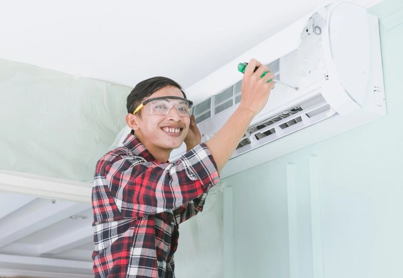 Teknisi membersihkan unit indoor AC — jasa bongkar pasang ac