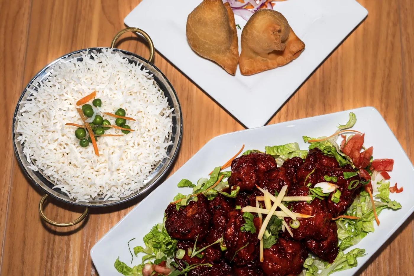 A Lilly's party pack spread: hand-folded samosas, chili chicken, and steamed basmati rice