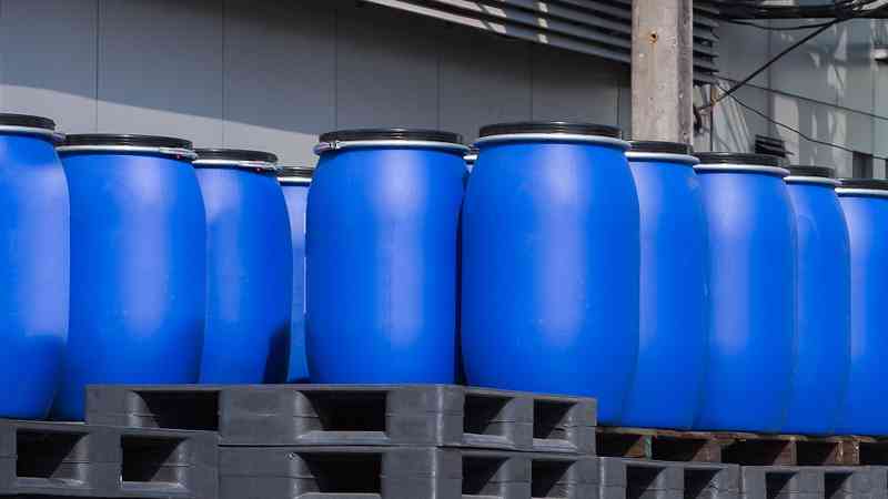 Photo of 55-gallon drums stacked on pallets outside a warehouse
