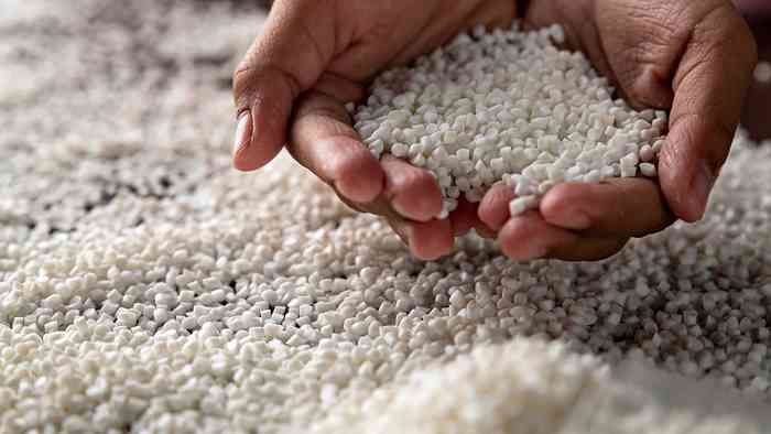 hands holding white plastic pellets